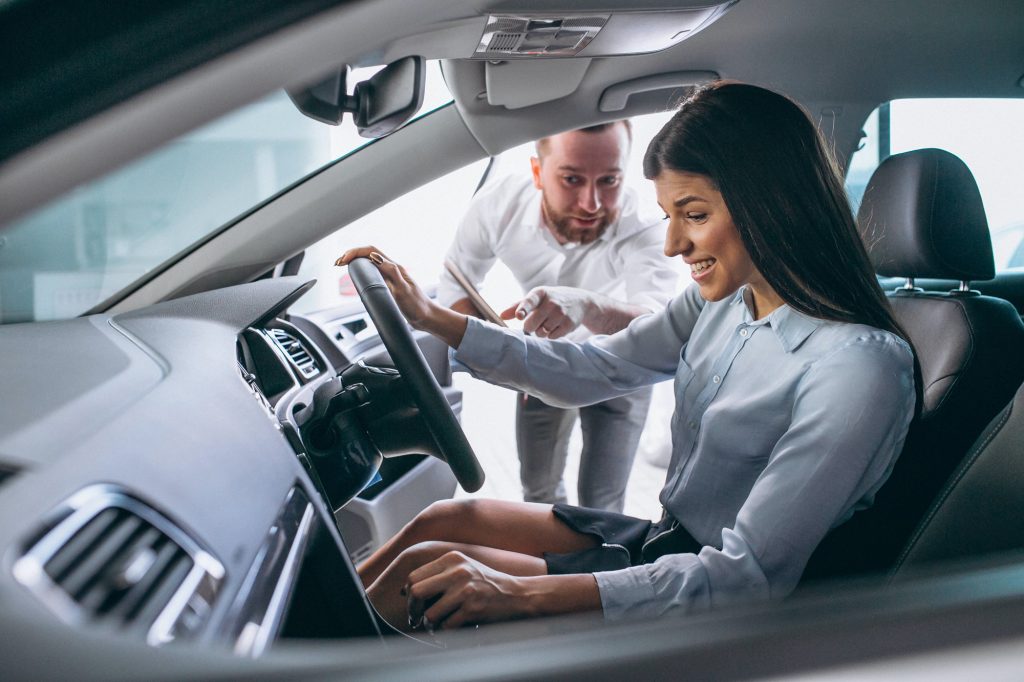 A man and woman smiling and discussing the car's features