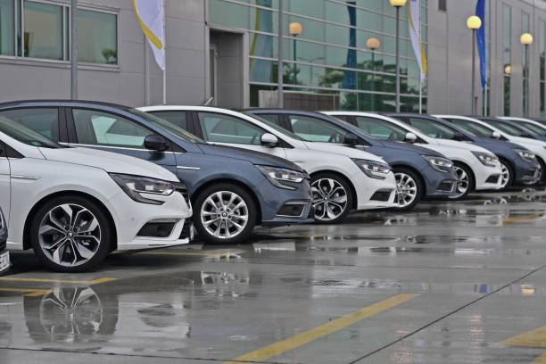 A row of modern cars parked outside a building with glass windows.