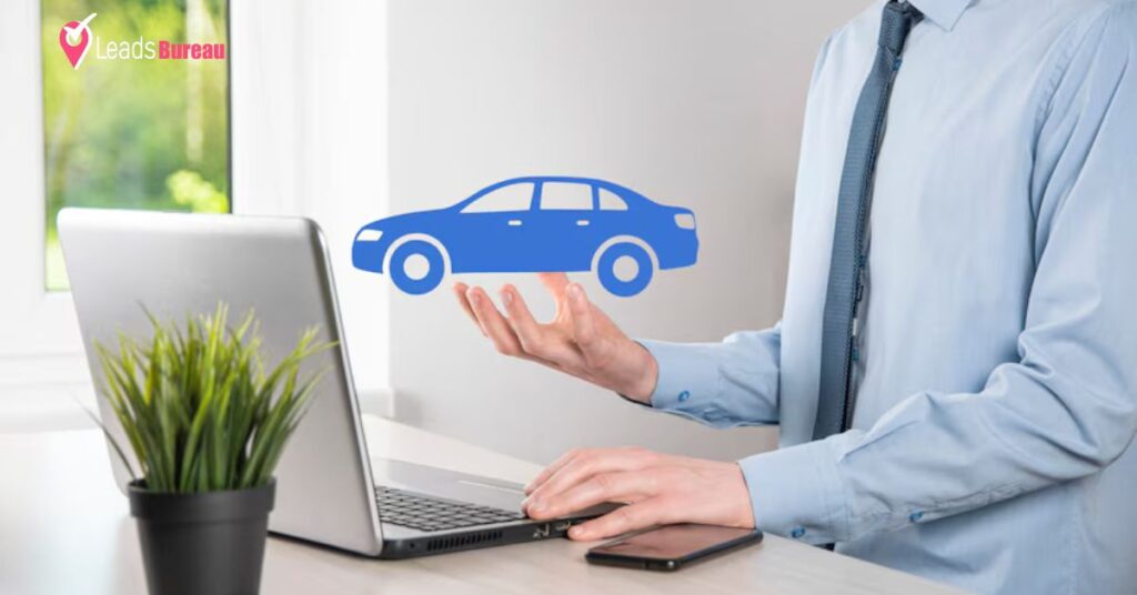 A person's hand shown new car icon and shown laptop and phone on table